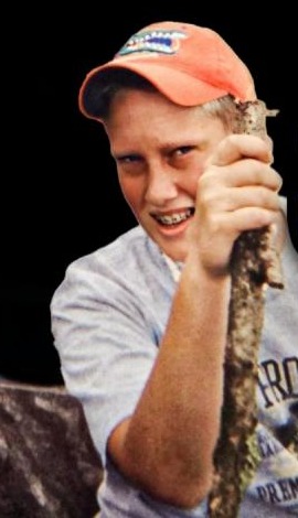 Andrew as a teenager in a cap, holding a walking stick